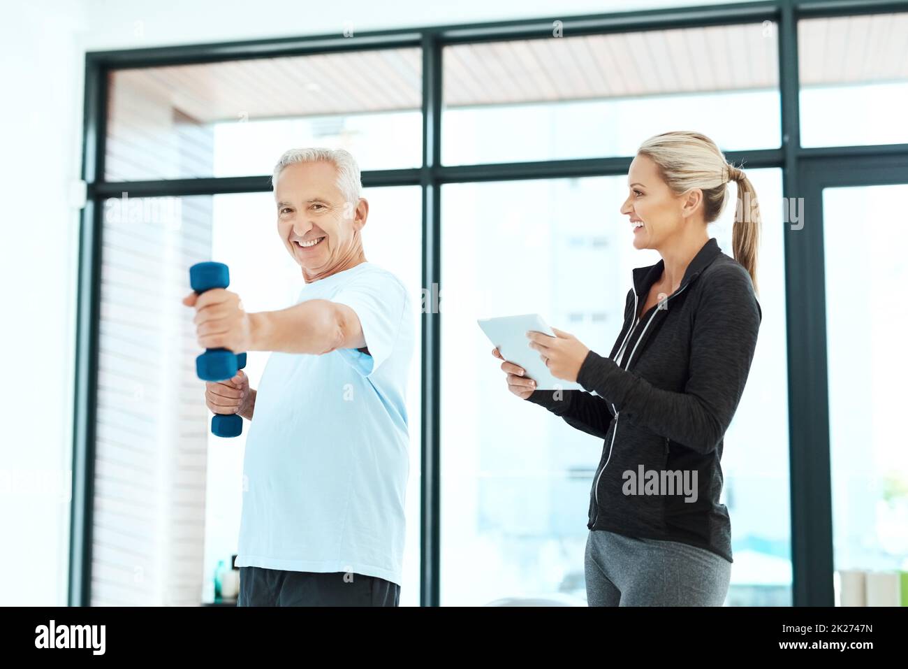 Tenere traccia dei suoi progressi. Shot di un fisioterapista che aiuta il suo paziente anziano con i suoi esercizi in un centro fitness. Foto Stock