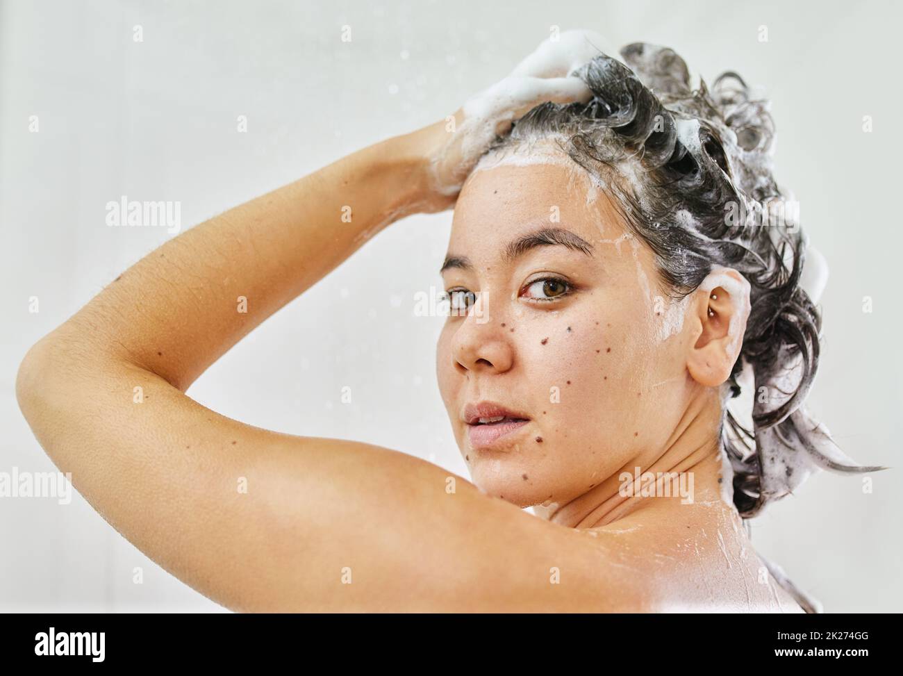 Ottenere i suoi capelli squeaky puliti. Shot di una giovane donna che lava i capelli con shampoo nella doccia a casa. Foto Stock
