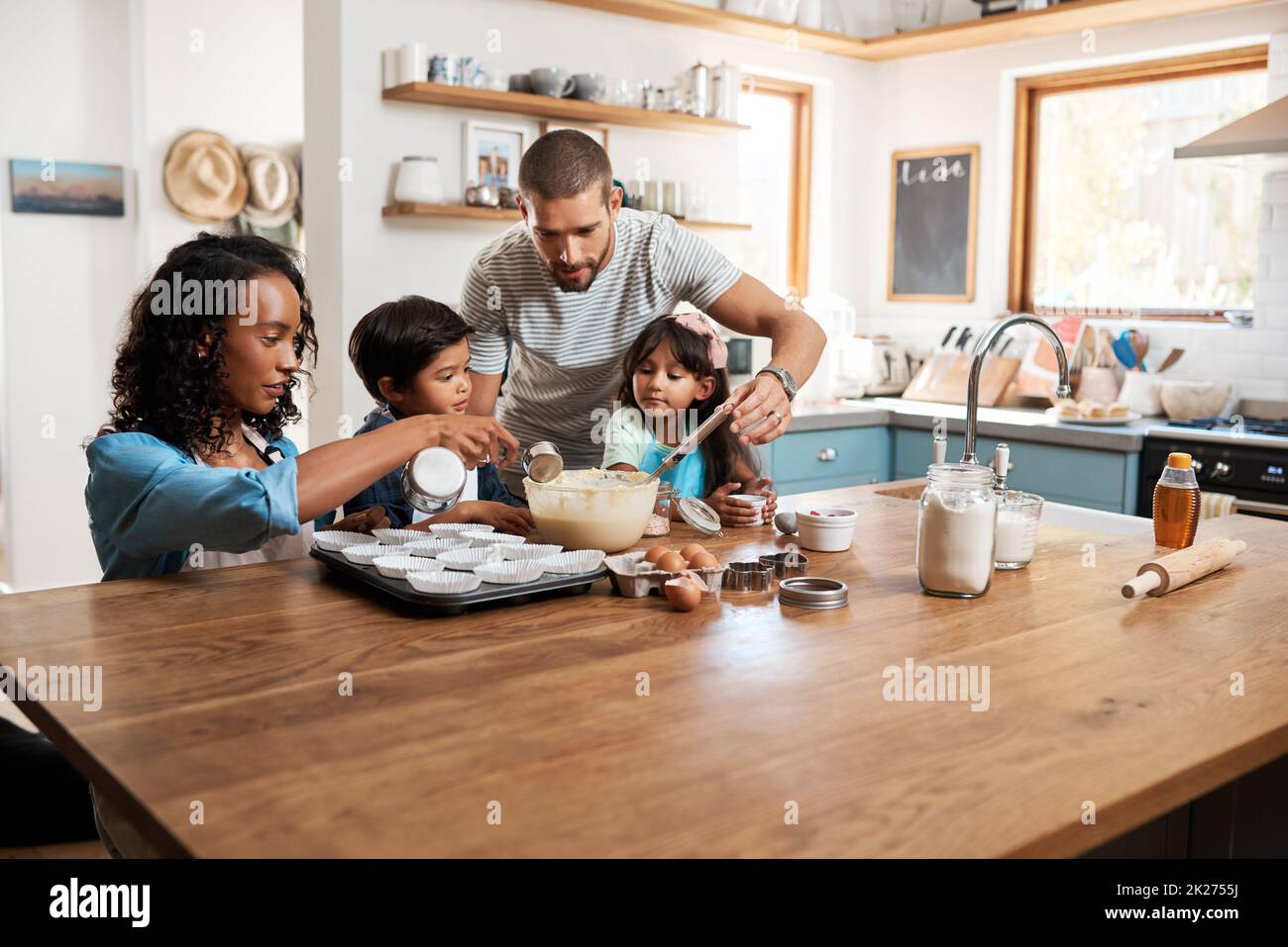 Tutta la famiglia si sta coinvolgendo. Scatto corto di una giovane coppia che cuoce a casa con i loro due bambini. Foto Stock