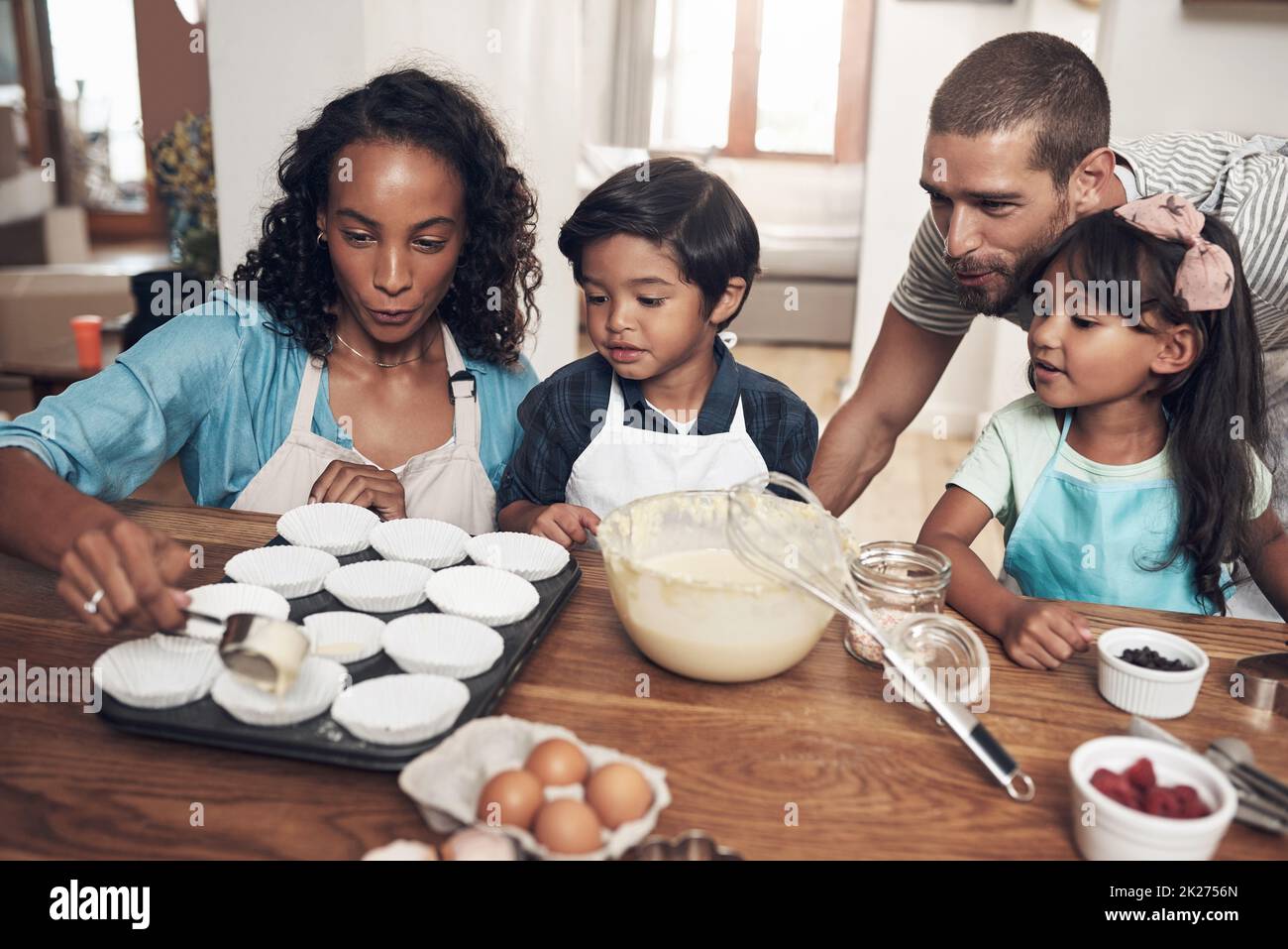 Vai a casa e ami la tua famiglia. Shot di una giovane coppia che cuoce a casa con i loro due figli. Foto Stock