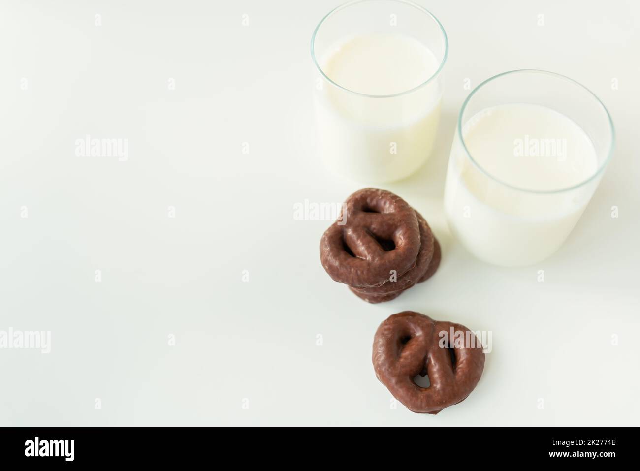 Biscotti di pan di zenzero al cioccolato giacono su un tavolo bianco insieme ad un bicchiere di latte. Luogo per un'iscrizione. Foto Stock
