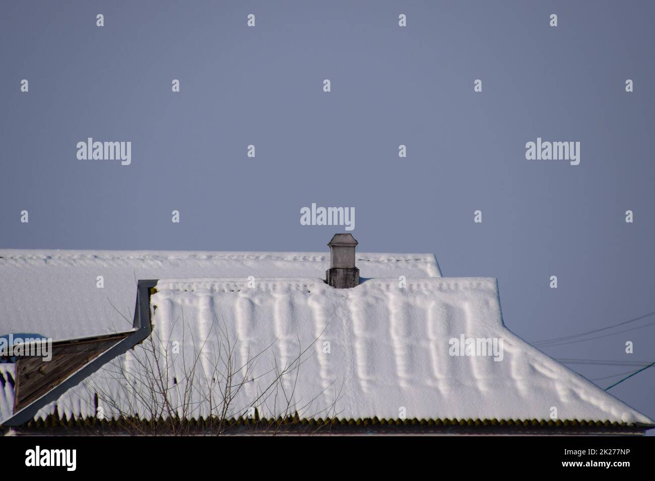 Il tetto della casa è nella neve. Casa con camino. Foto Stock