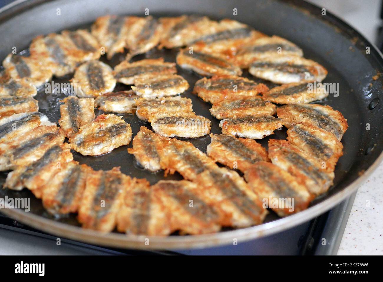L'acciuga è fritta in una padella, cucinando l'acciuga di stile turco, pesce fritto Foto Stock