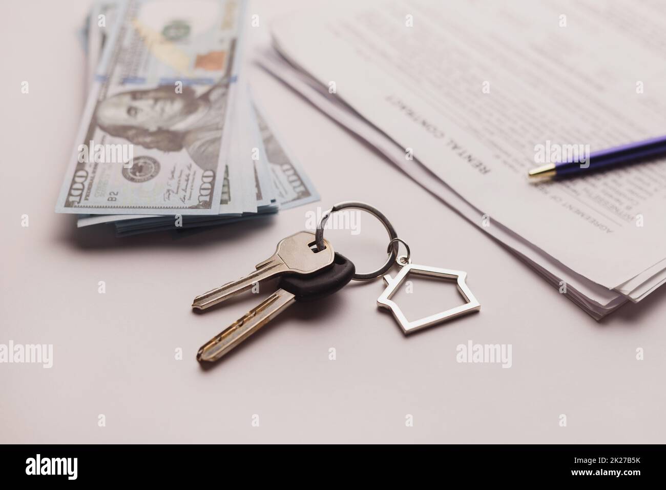 Contratto di acquisto immobiliare con denaro e chiavi di casa su tavolo bianco. Foto Stock