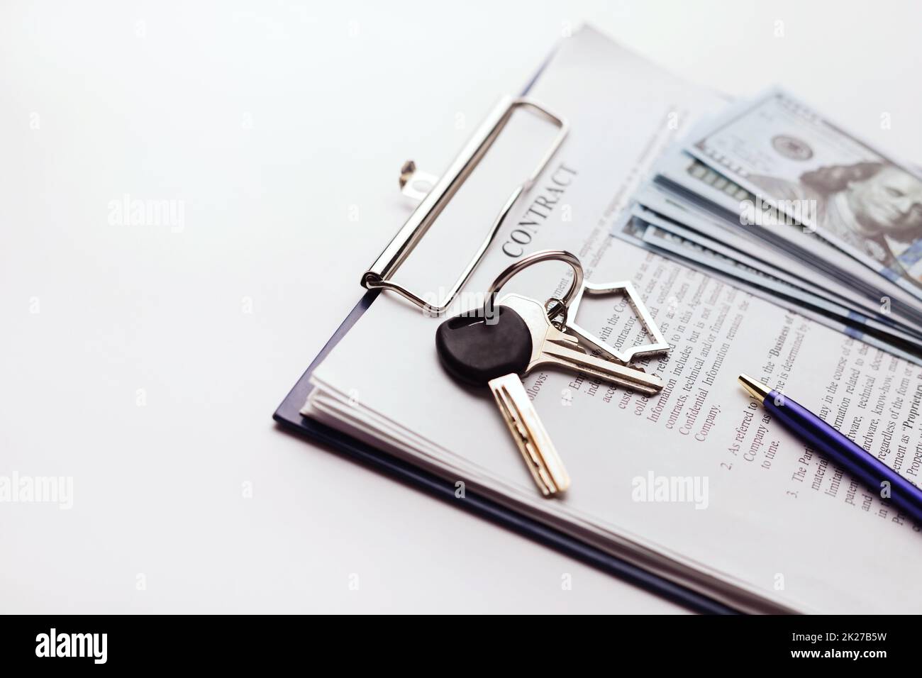 Contratto di acquisto immobiliare con denaro e chiavi di casa su tavolo bianco. Foto Stock