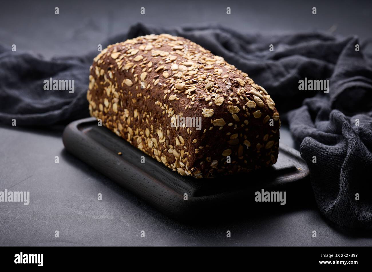 pane di farina di segale quadrata al forno con farinata d'avena su sfondo nero Foto Stock