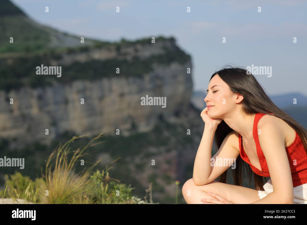 Donna asiatica in rosso che riposa in montagna Foto Stock