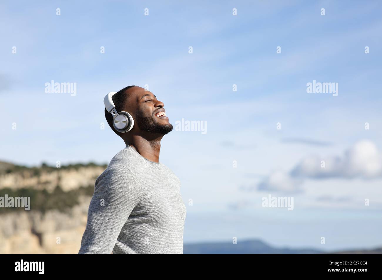 Uomo felice che respira ascoltando musica all'aperto Foto Stock