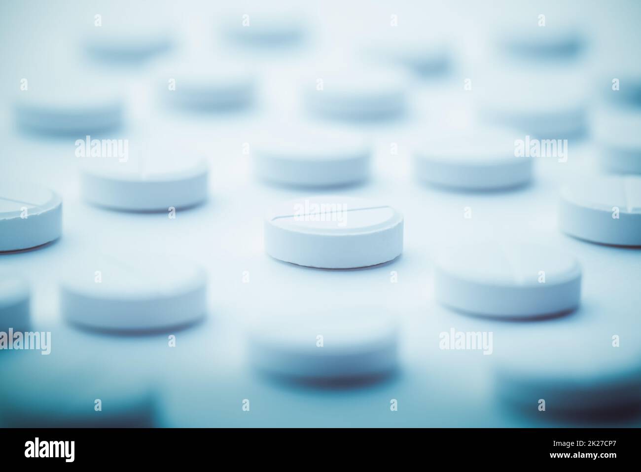 Un mucchio di pillole bianche sparse su uno sfondo bianco luminoso. Messa a fuoco selettiva. Foto Stock