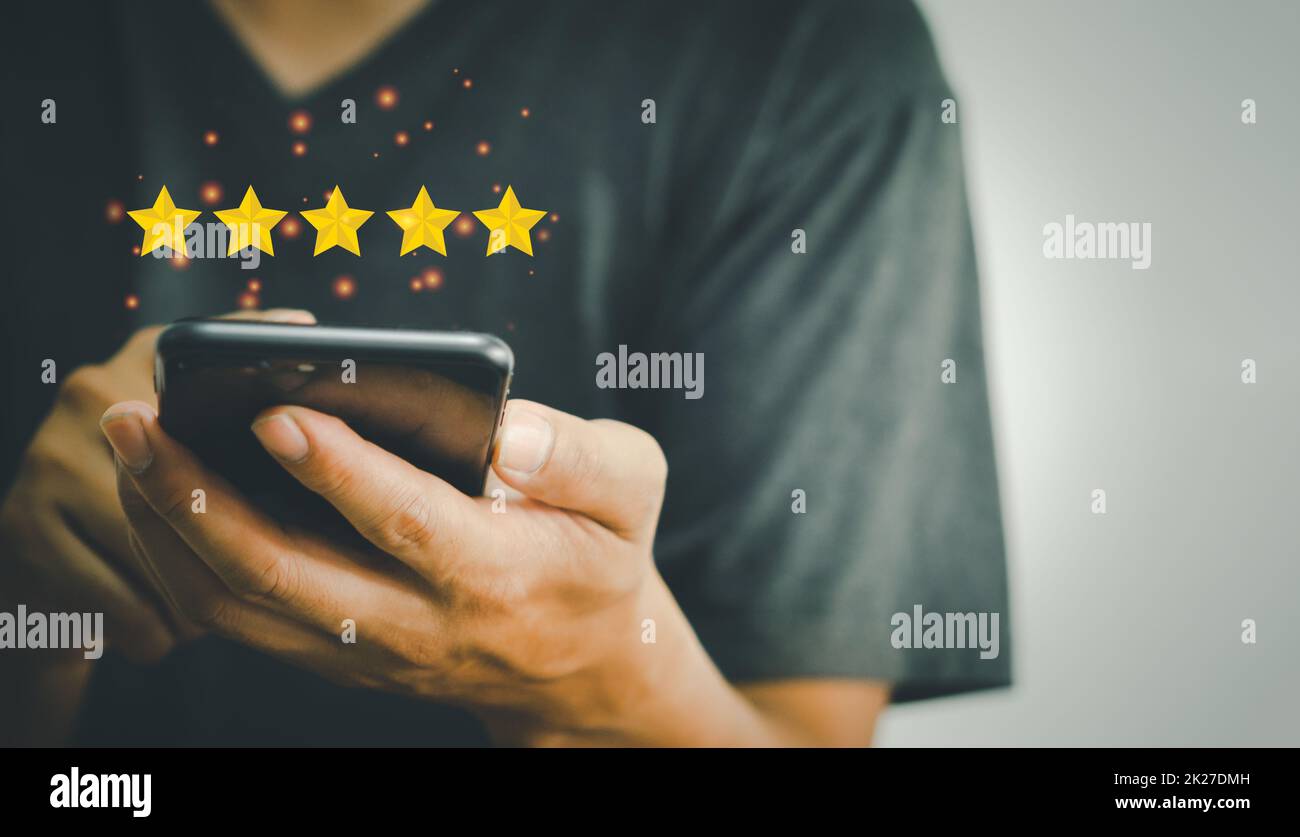 Mano usando il telefono che tiene 5 stelle sulle mani.soddisfazione del cliente e concetto di valutazione di indagine di vendita Foto Stock