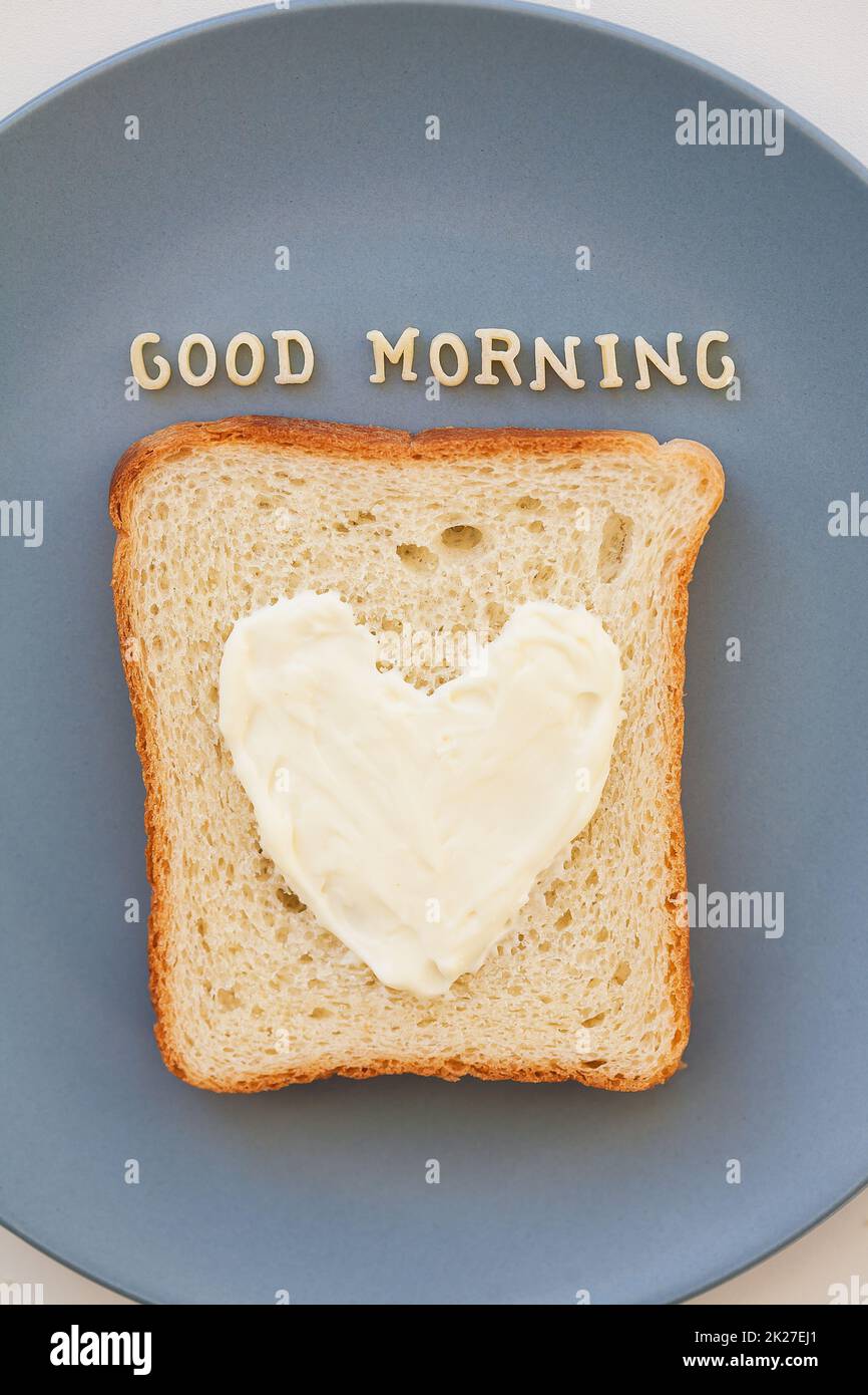 sandwich per la colazione a forma di cuore con formaggio su una targa blu iscrizione buongiorno Foto Stock