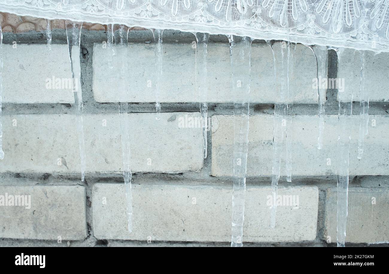 Ghiaccioli appesi, gocciolando. D'inverno a primavera. Profondità poco profonda di campo. Modello di cristallo di ghiaccio appeso un pace di legno. Foto Stock