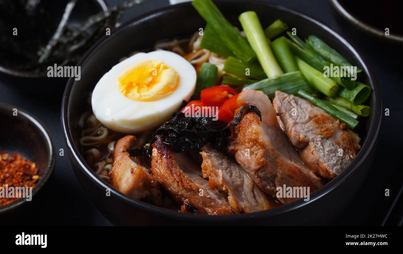 Zuppa di ramen con uova sode, verdure, maiale, salsa di soia. Tonkotsu ramen giapponese, spaghetti di brodo di ossa di maiale Foto Stock