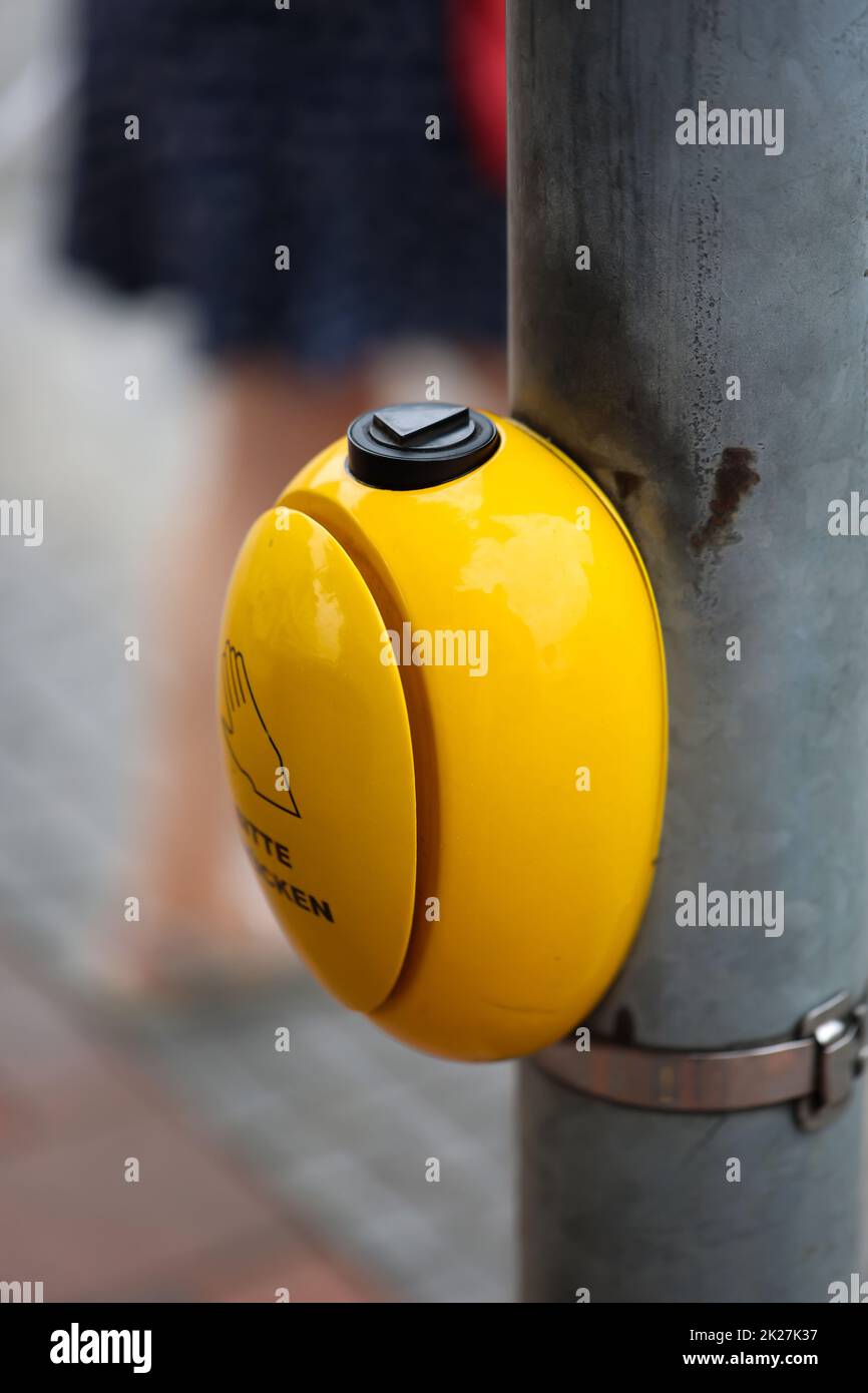 Ad un incrocio pedonale si trova un pulsante giallo per un semaforo. Foto Stock