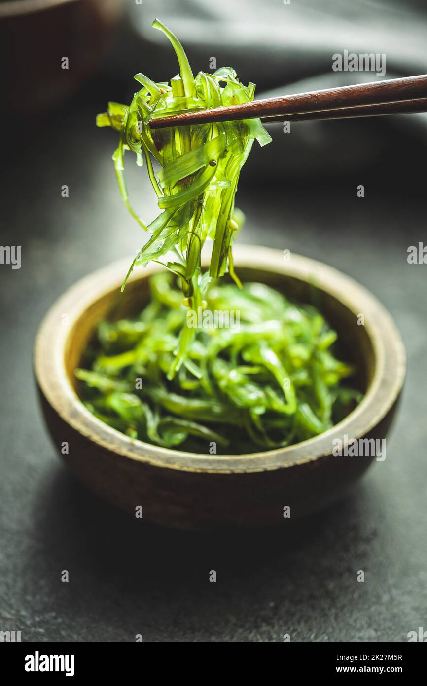 Wakame verde. Insalata di alghe nel recipiente sul tavolo nero. Foto Stock