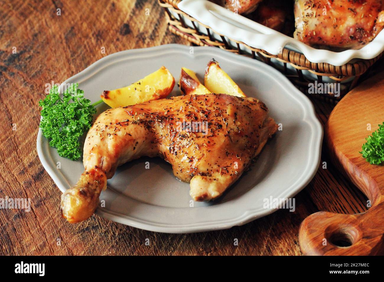Coscia di pollo alla griglia con patate per guarnire. Sfondo di legno. Foto Stock
