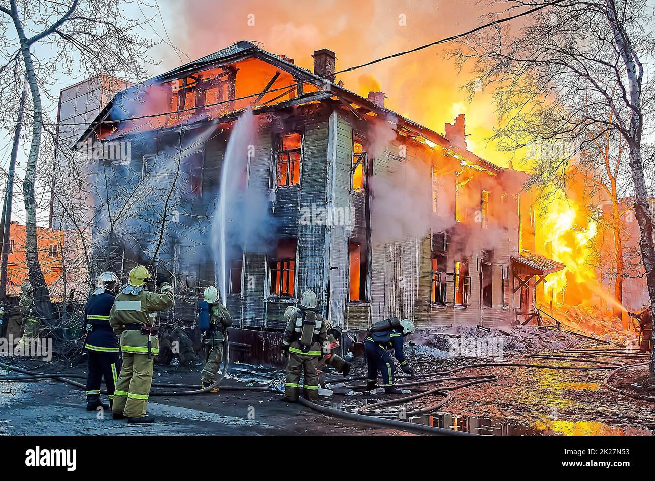I vigili del fuoco spengono un incendio in una casa di legno a due piani Foto Stock