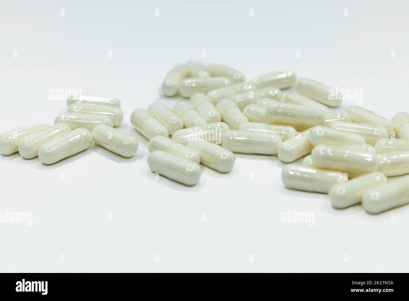 Primo piano di una pila di capsule bianche. Farmaci su sfondo bianco Foto Stock