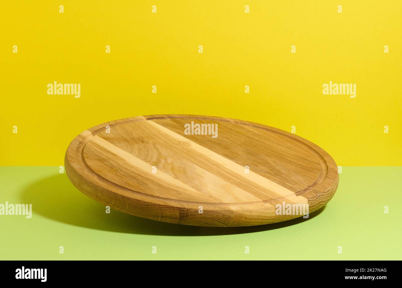 tavola rotonda di legno della cucina della pizza su sfondo giallo-verde, utensili levitate Foto Stock