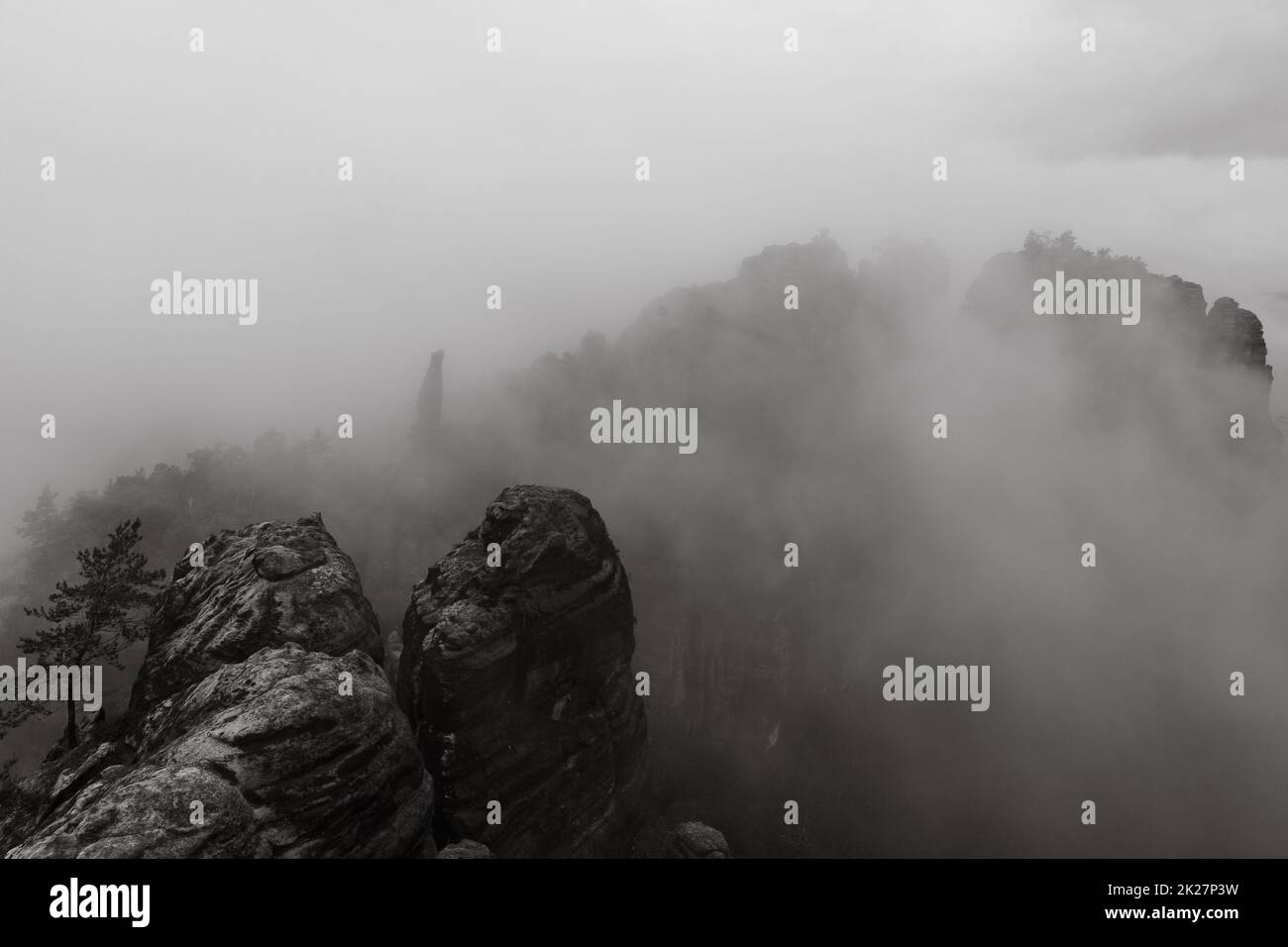 Una mattina presto nuvolosa in montagna. Schrammsteine - un gruppo di rocce è un lungo, steso-fuori, molto frastagliato nelle montagne di arenaria dell'Elba situato nella Svizzera Sassone nella Germania orientale. Bianco e nero. Foto Stock