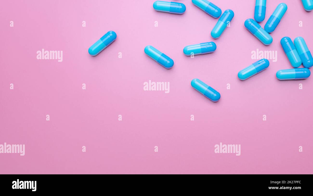 Vista dall'alto capsule pills su sfondo rosa. Farmaci da prescrizione. Capsule blu pillole. Industria farmaceutica. Medicamento e farmacologia. Sviluppo di farmaci e ricerca di nuovi farmaci. Capsule pills industria. Foto Stock