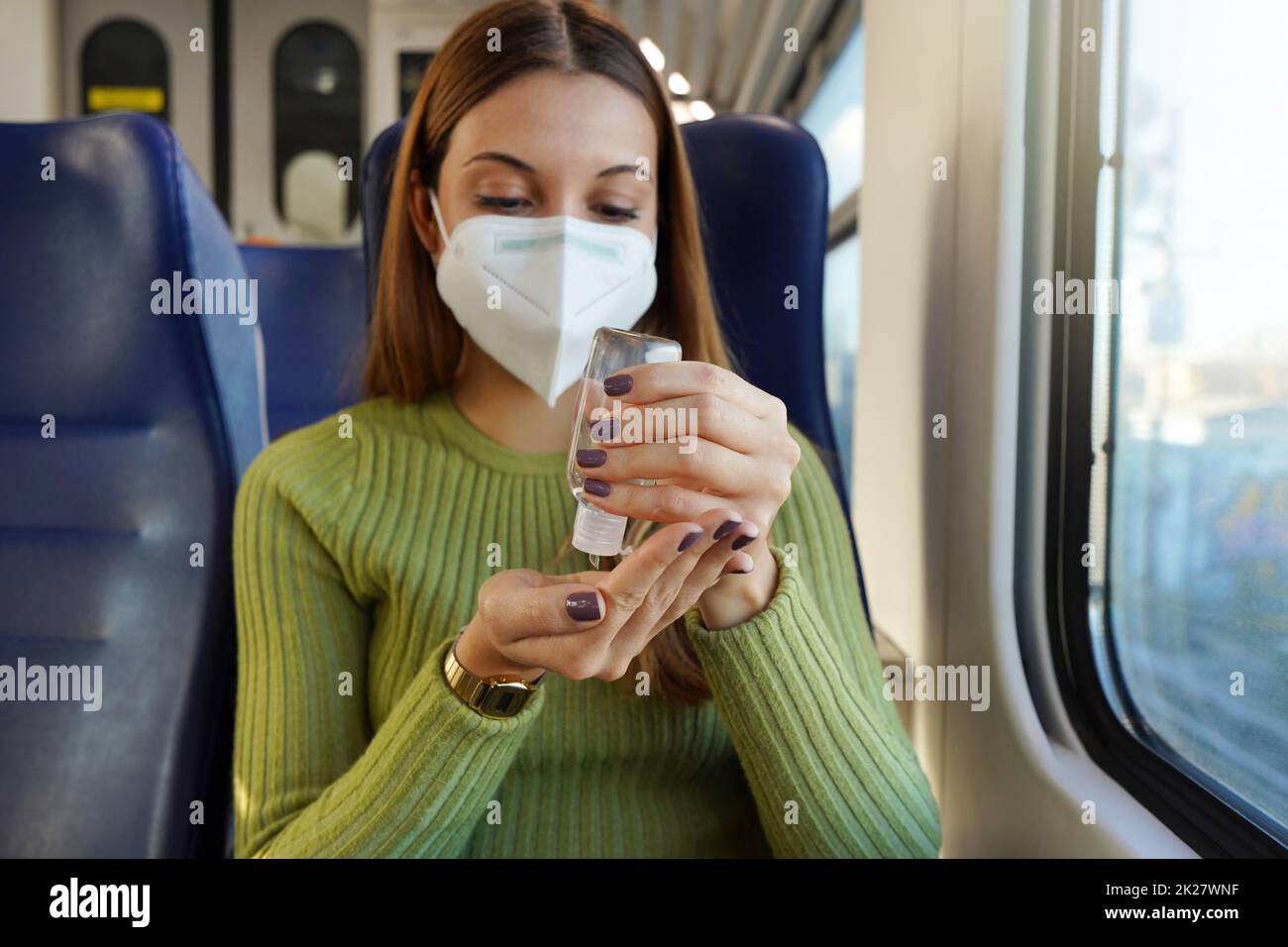 Donna d'affari con maschera medica viso utilizzando gel di alcool sanitizzante mani sui trasporti pubblici. Concetto antisettico, igienico e sanitario. Messa a fuoco a portata di mano. Foto Stock