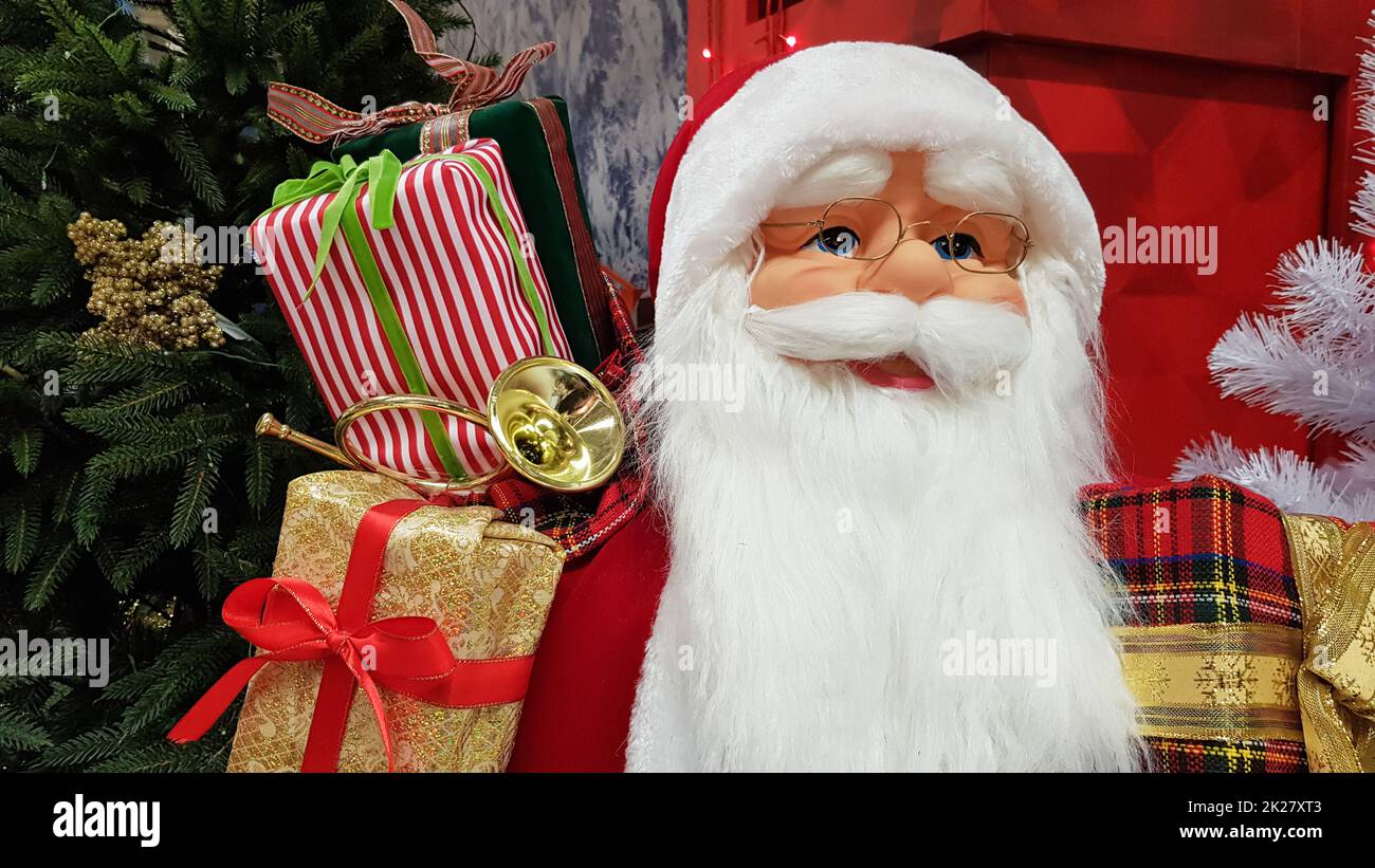 Il ritratto fotografico di una felice bambola giocattolo Babbo Natale con una borsa di regali simboleggia l'arrivo di Natale e Capodanno. Atmosfera festiva, concetto di vacanza. Foto Stock Il ritratto fotografico di una felice bambola giocattolo Babbo Natale con una borsa di regali simboleggia l'arrivo di Natale e Capodanno. Atmosfera festiva, concetto di vacanza. Foto Stock