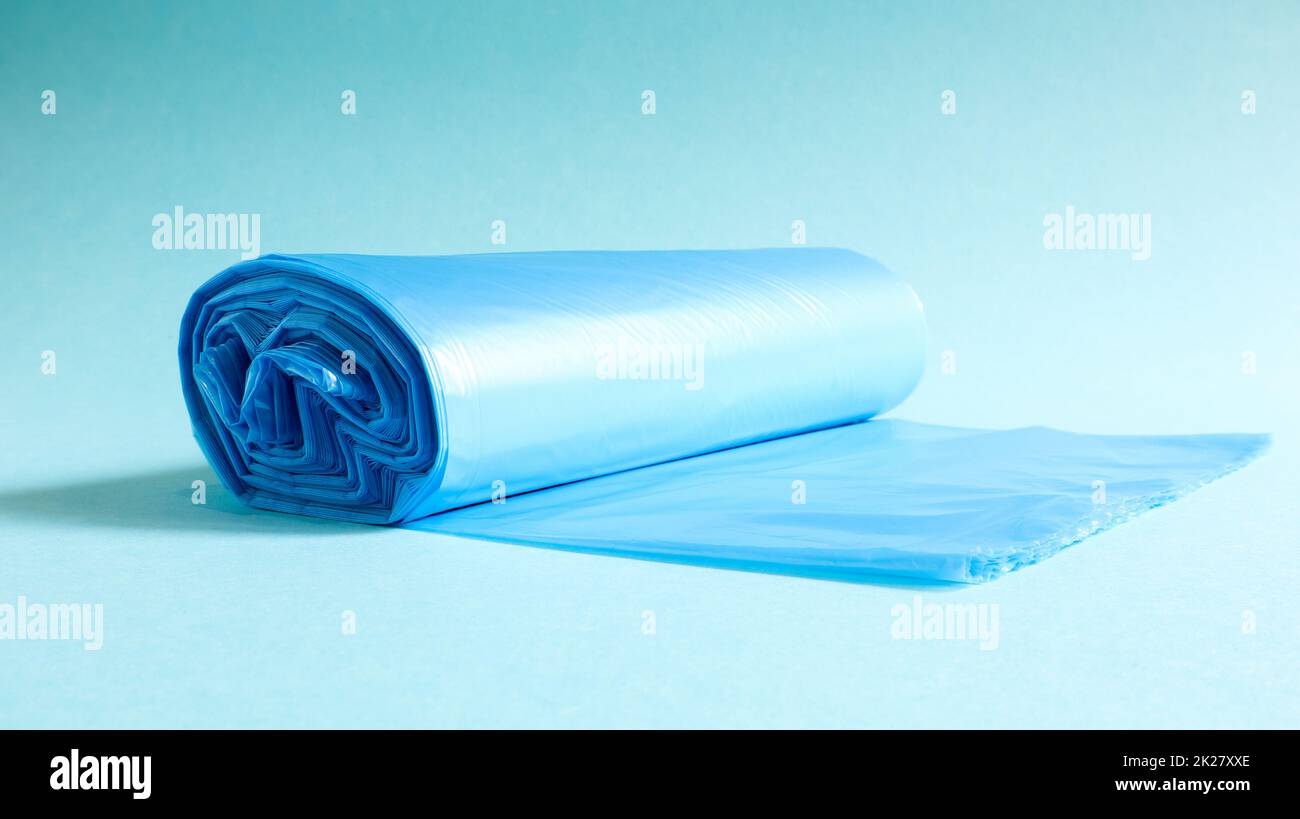 Un rotolo di sacchetti di plastica per rifiuti in blu su sfondo blu. Sacchetti che sono progettati per ospitare i rifiuti in loro e utilizzati a casa e messi in vari contenitori di rifiuti. Foto Stock
