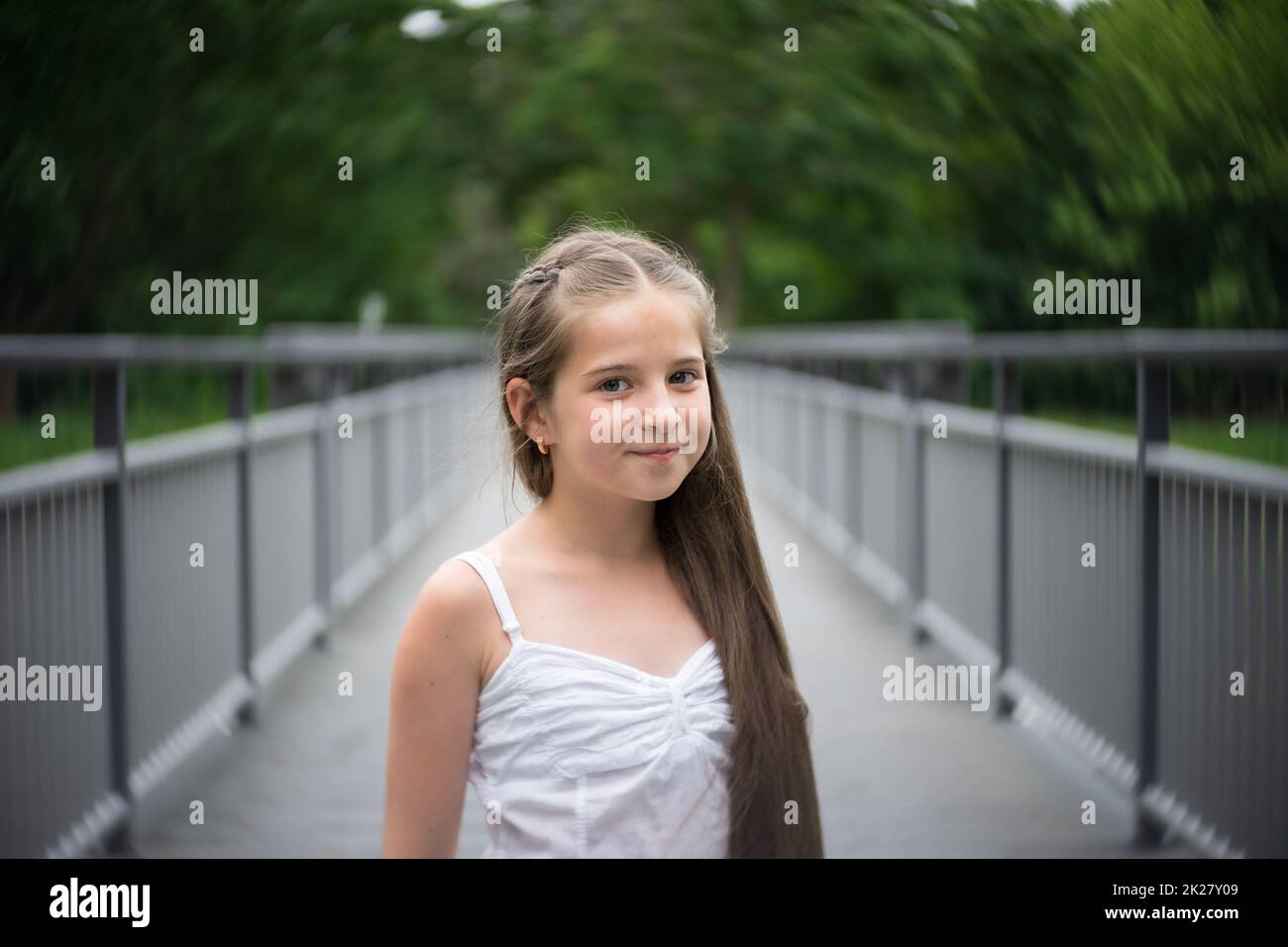Ritratto di una bella ragazza con lunghi capelli in piedi su un ponte. Foto Stock