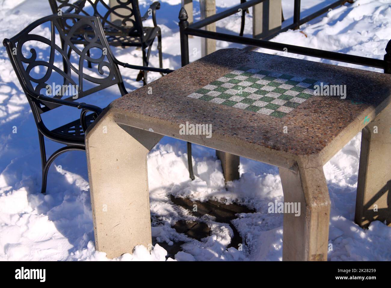 Un tavolo di scacchiera in cemento con una sedia in ferro pesante Foto Stock