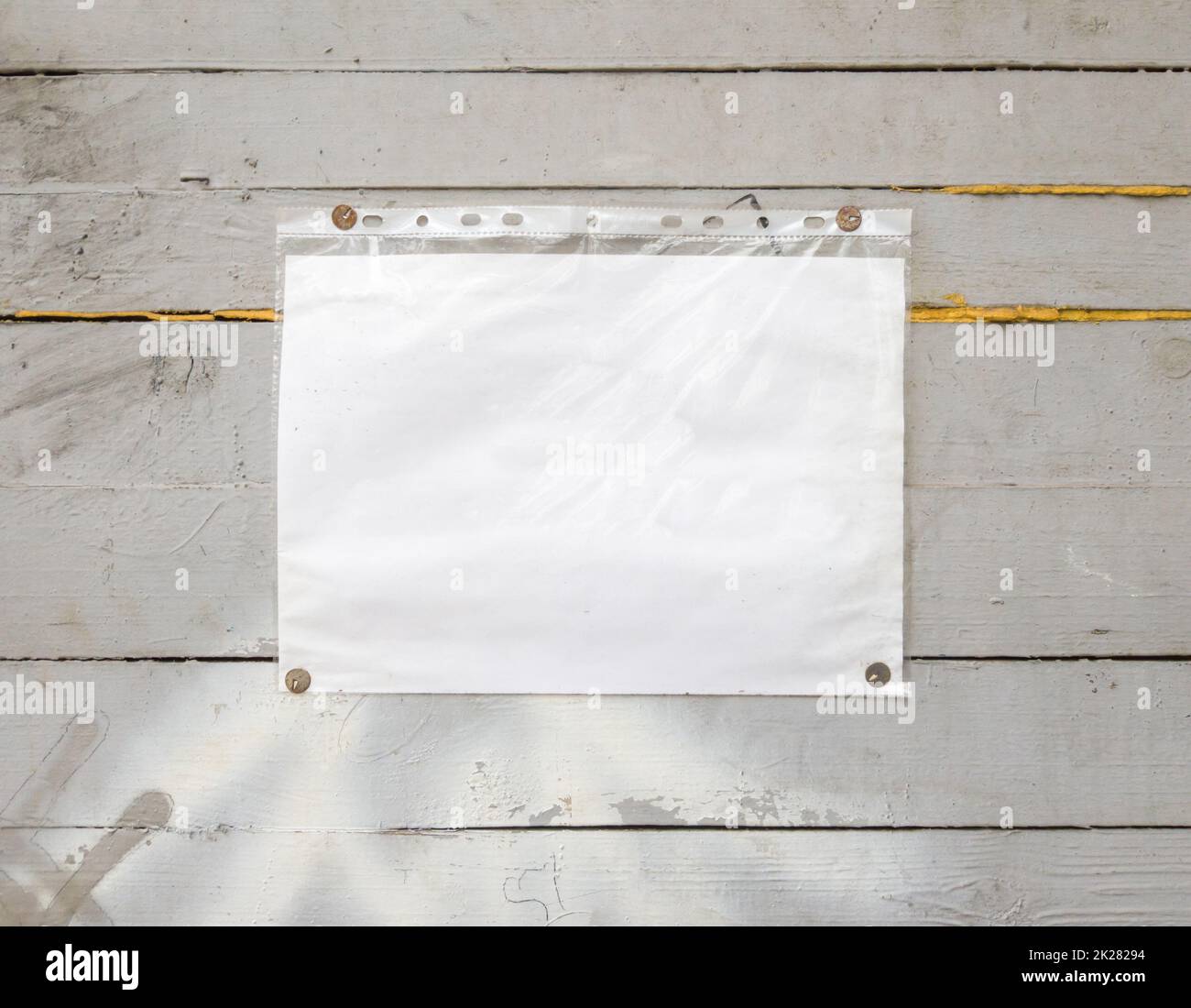 Insegna di carta bianca con rivetti, sfondo vintage su un vecchio sfondo grigio in legno. Parete di legno testurizzata, pesa un bianco bianco bianco cartone bianco illuminato dal sole, primo piano Foto Stock