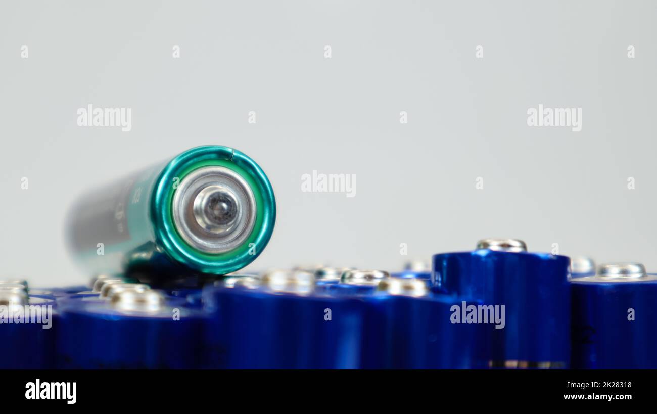 Numerose batterie alcaline AA e AAA su sfondo bianco. Concetto di riciclaggio ecologico. I terminali delle batterie monouso sono vicini e formano uno sfondo bellissimo. Fonte di energia. Foto Stock