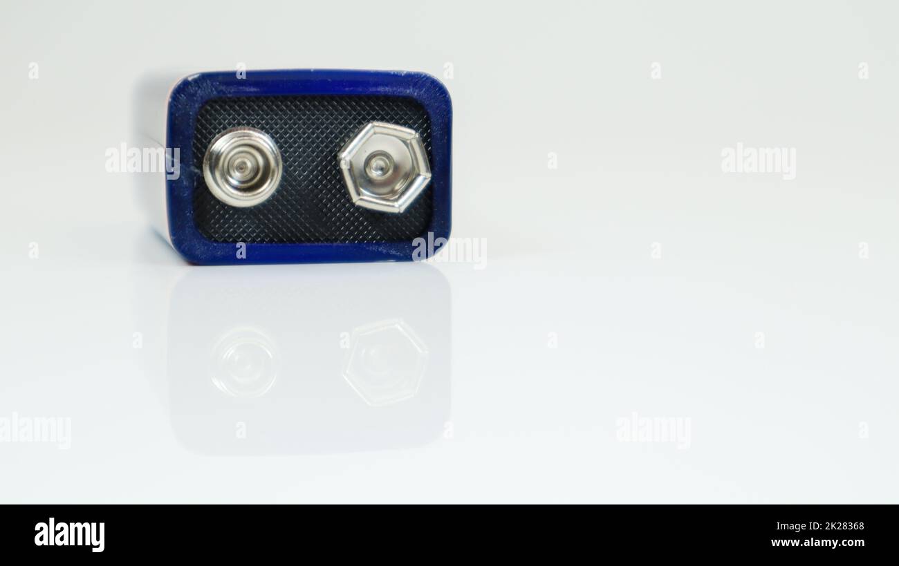 Una batteria blu da PP3 V su sfondo bianco con riflesso. Batteria principale per alimentatori personali. Primo piano di un connettore della batteria graffiato e usato. Foto Stock