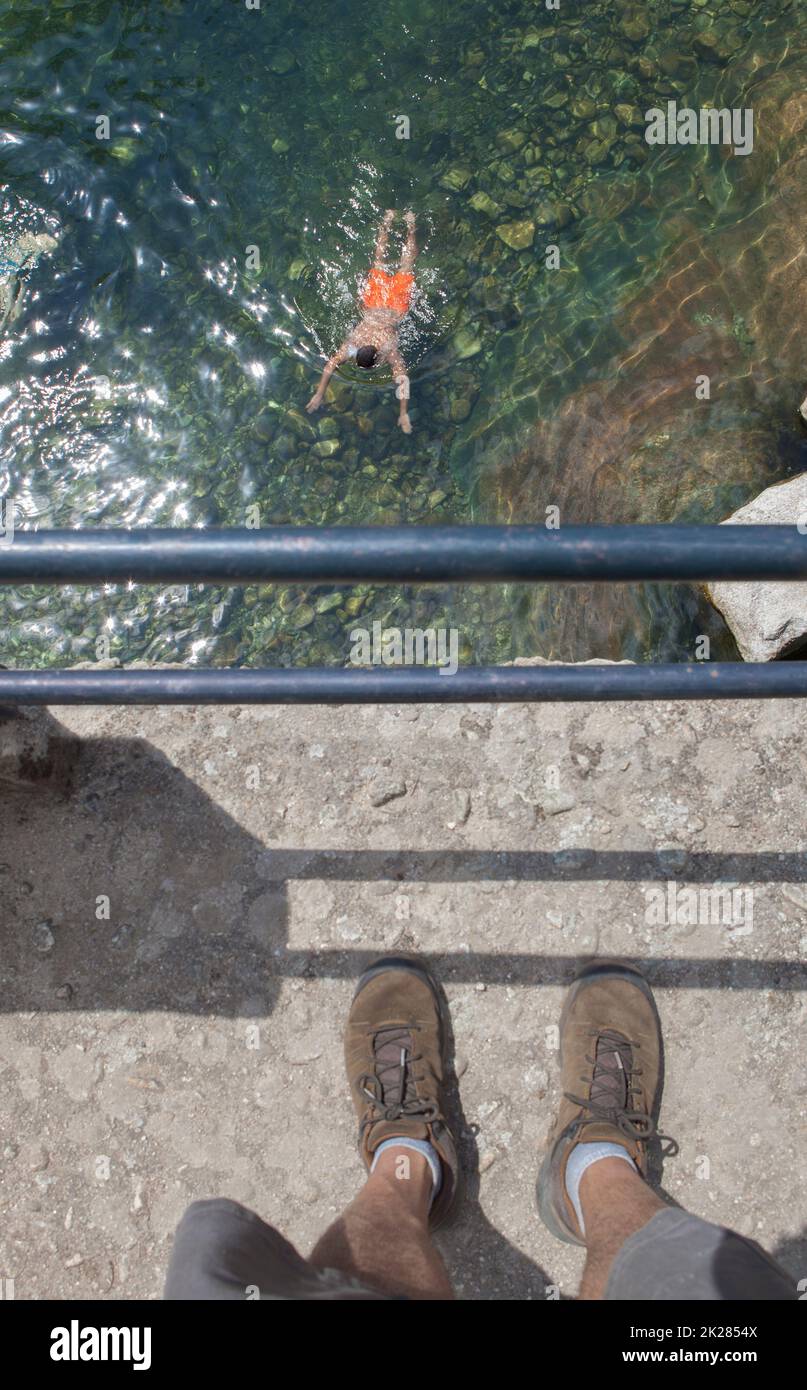 Trekker osservare nuotatore dal parapetto ponte. La Maquina piscina naturale, acque cristalline nel cuore della contea di la vera, Caceres, Estremadura Foto Stock