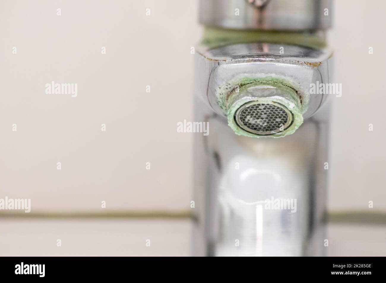 Il vecchio rubinetto graduato come manico calcificato in cromo nel bagno ha bisogno di manutenzione e decalcificazione con detergenti per fermare la perdita e migliorare l'igiene batteri del vecchio manico con la povertà di goccioline Foto Stock