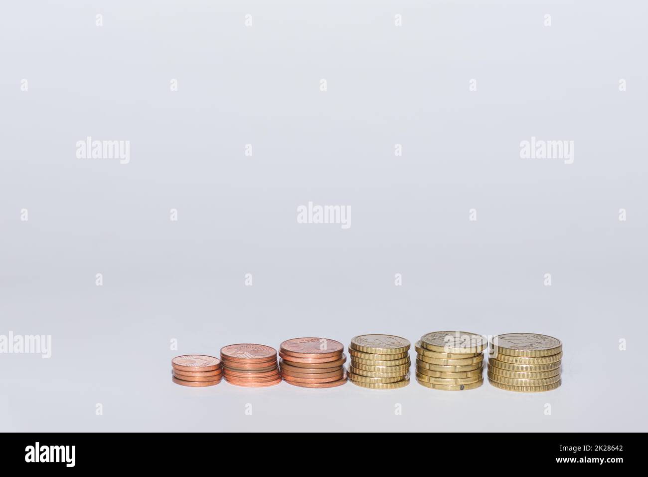 diverse monete in euro impilate in una fila che aumentano di valore con il grigio Foto Stock