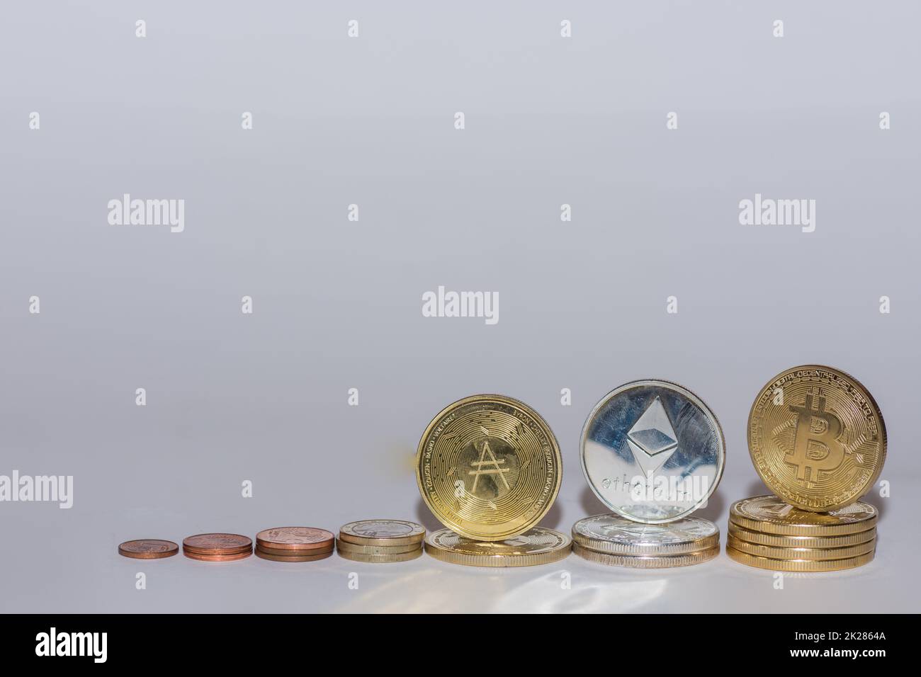 monete in euro e cripto monete bitcoin etere e ada in fila con sfondo grigio obliquo Foto Stock