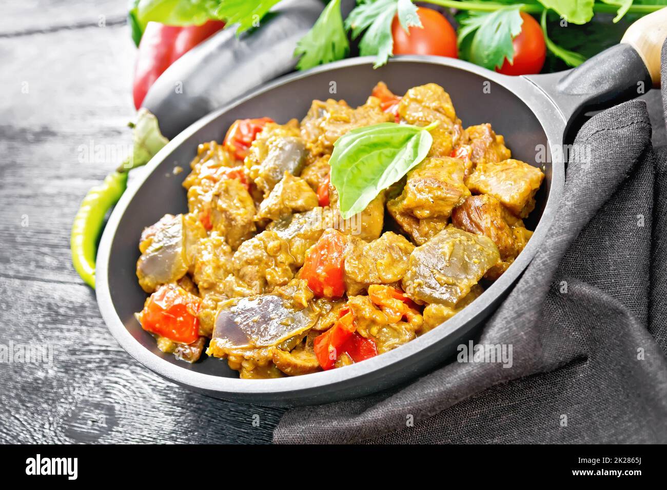 Carne con melanzane e pepe in padella su tavola nera Foto Stock