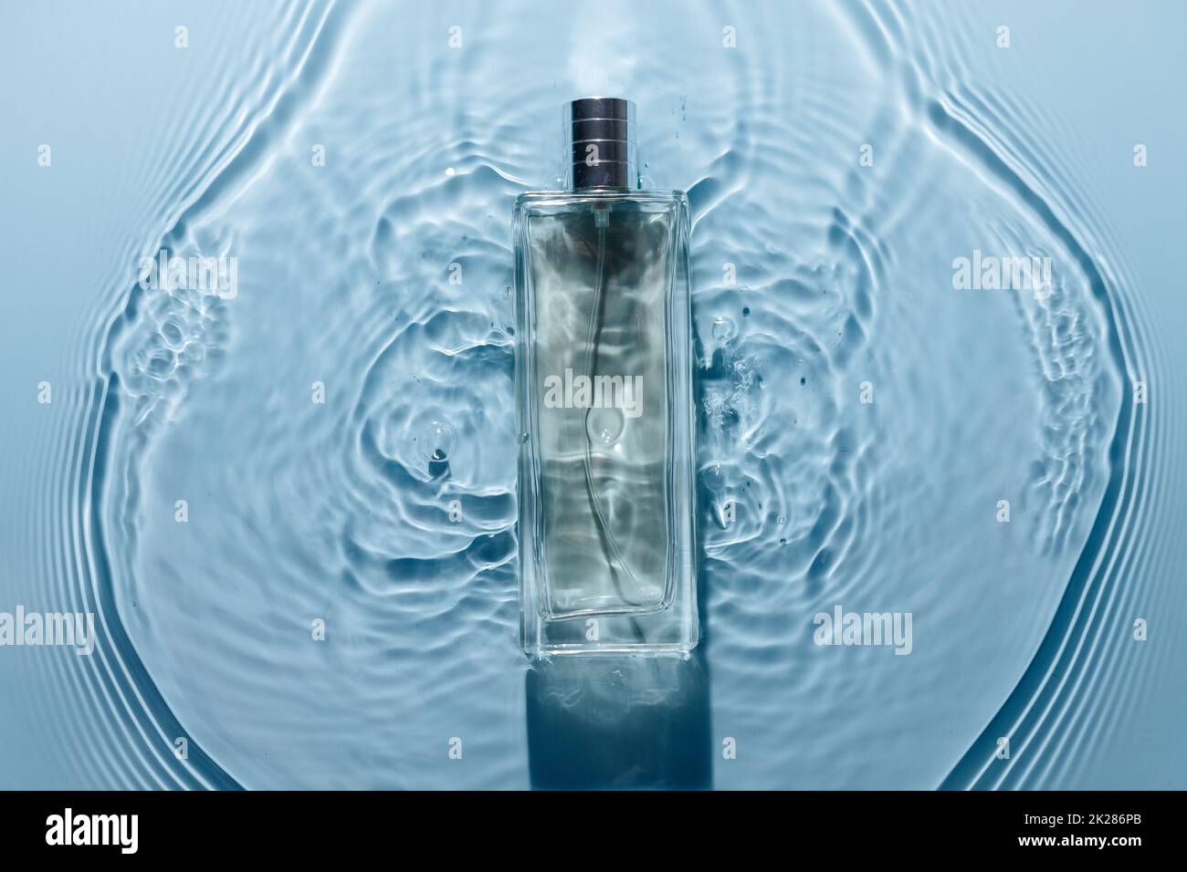 Bottiglia di profumo su sfondo ondulato blu d'acqua. Fragranza fresca di mare. Puro e freddo. Foto Stock