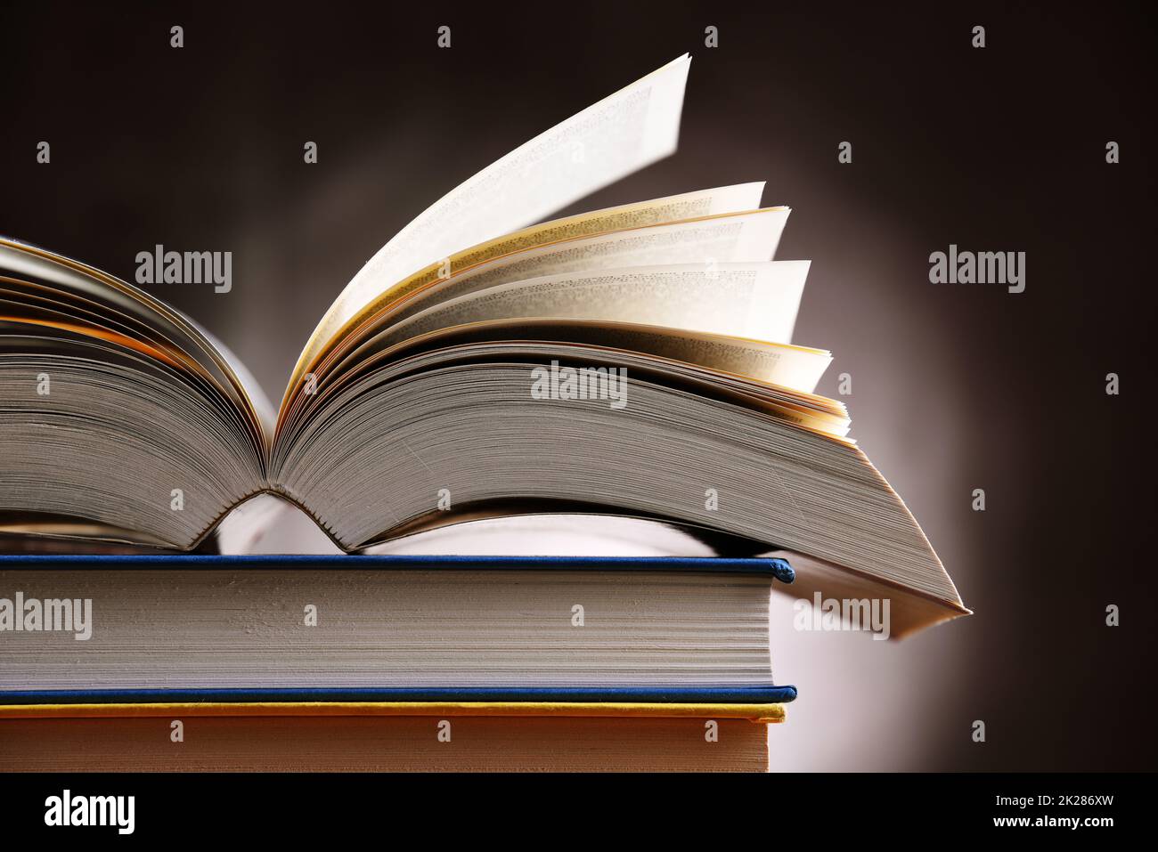 Una composizione con un libro aperto che giace su una pila di altri libri  Foto stock - Alamy