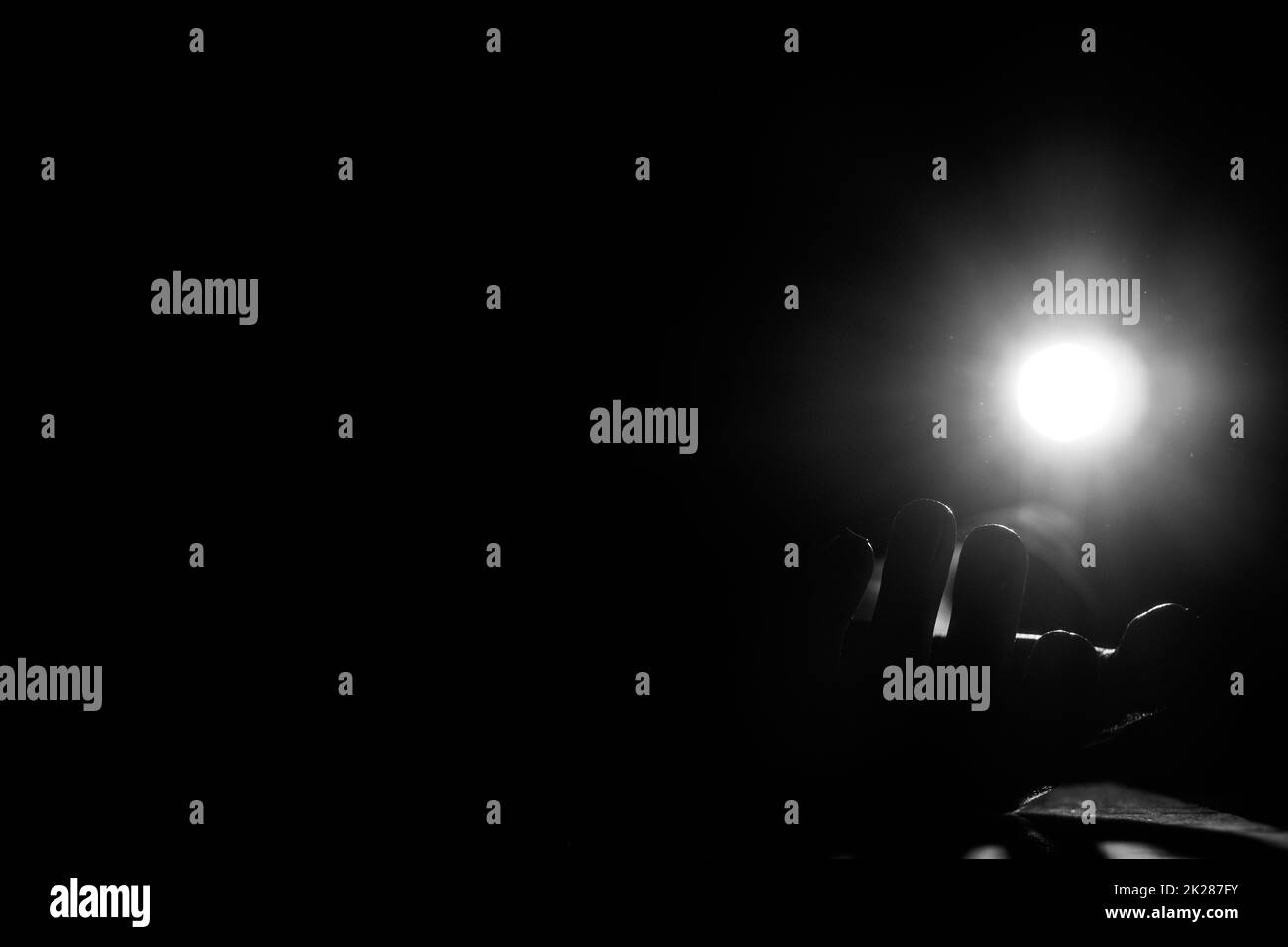 La mano di una donna al buio si trova a terra alla luce di una lanterna, foto in bianco e nero, paura e orrore, mano Foto Stock