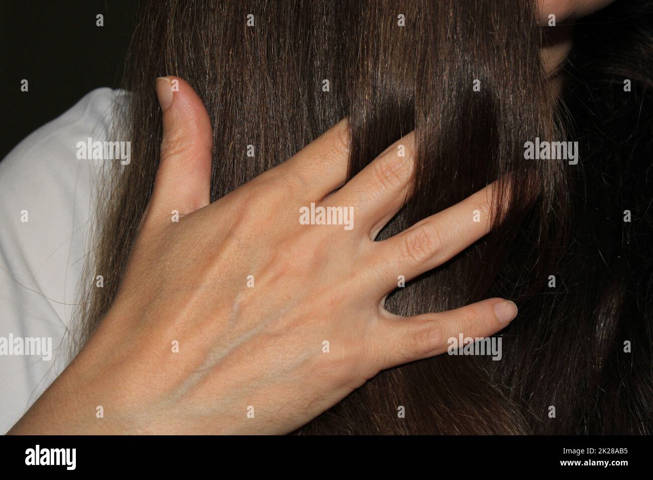 Una ragazza con capelli lunghi e scuri la mise tra i capelli. Cura dei capelli. Problema di perdita dei capelli. Foto Stock