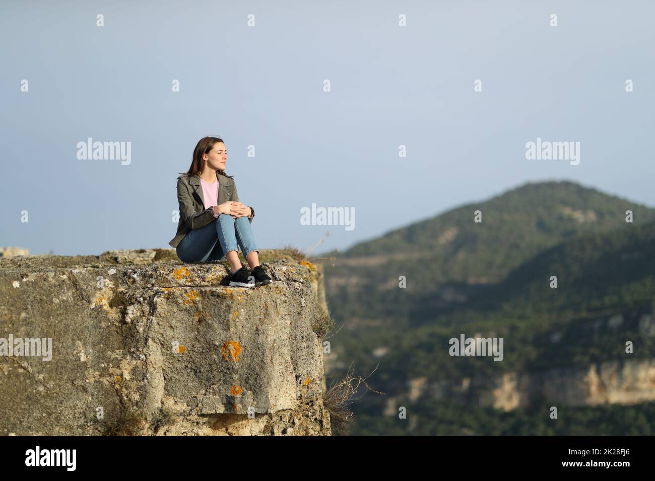 Donna casual contemplare dalla cima di una scogliera Foto Stock