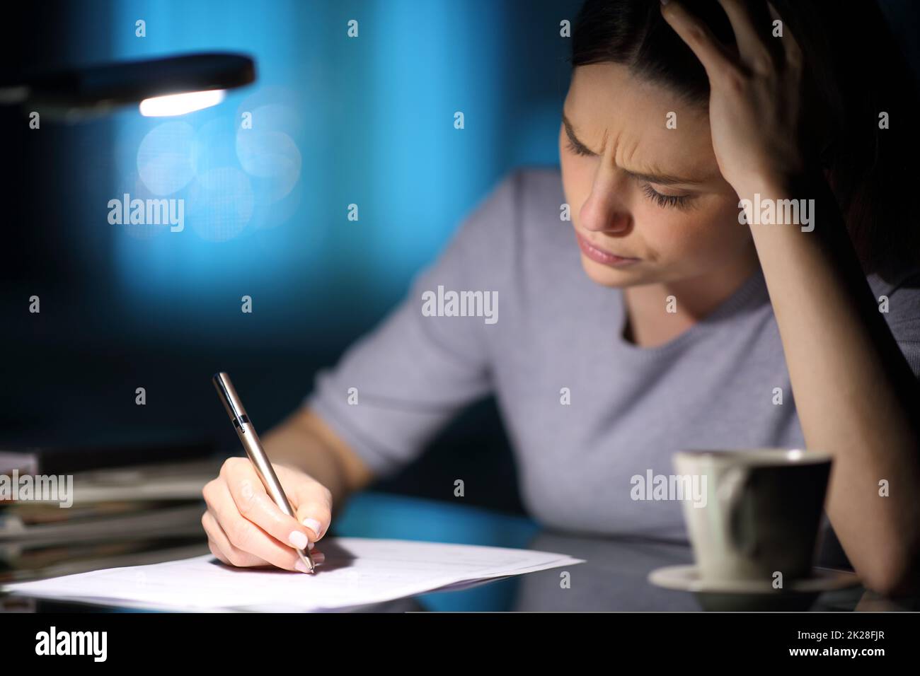 Donna preoccupata che compila il modulo nella notte a casa Foto Stock