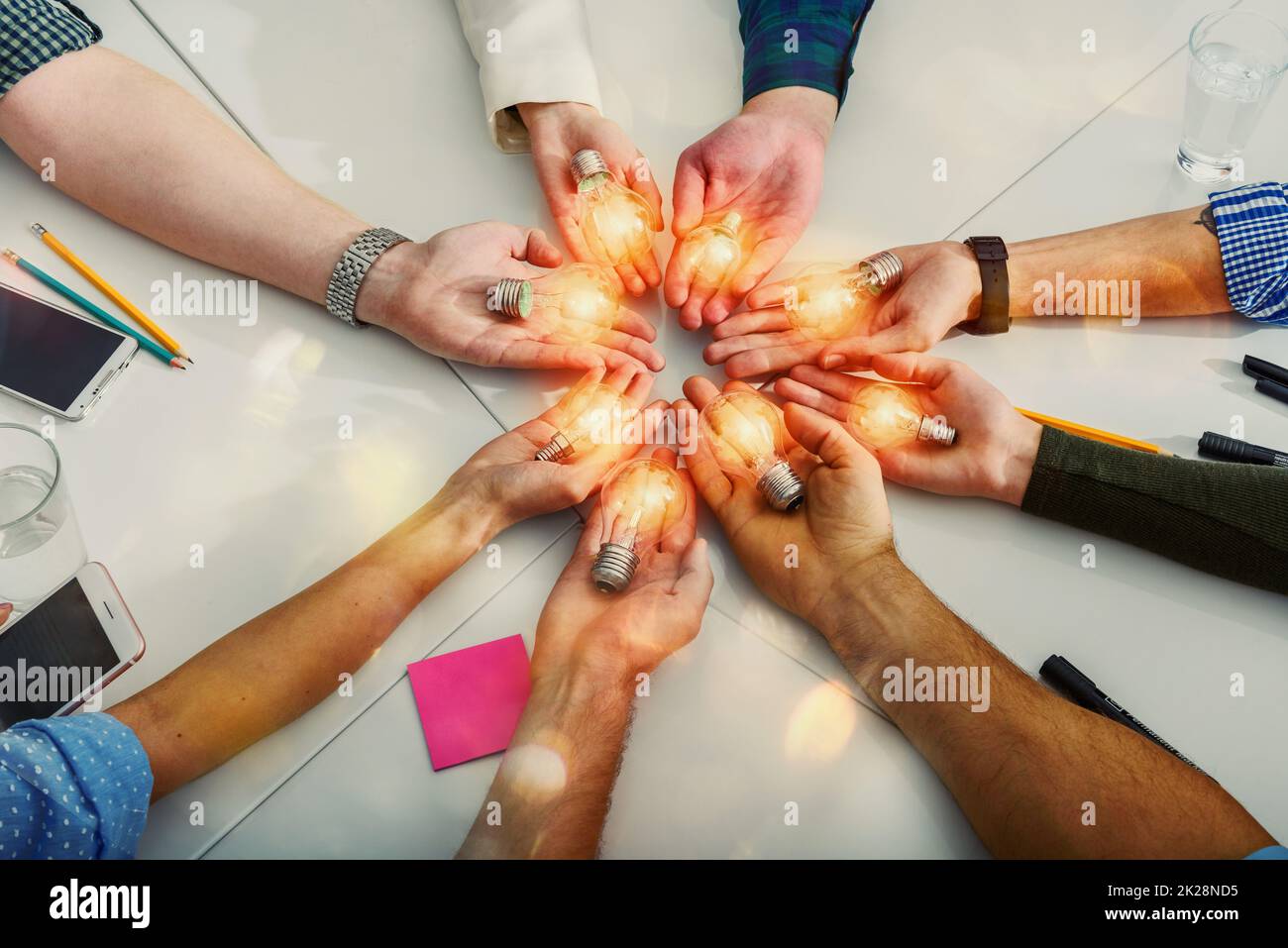 Concetto di lavoro di squadra e brainstorming con uomini d'affari che condividono un'idea con una lampada Foto Stock