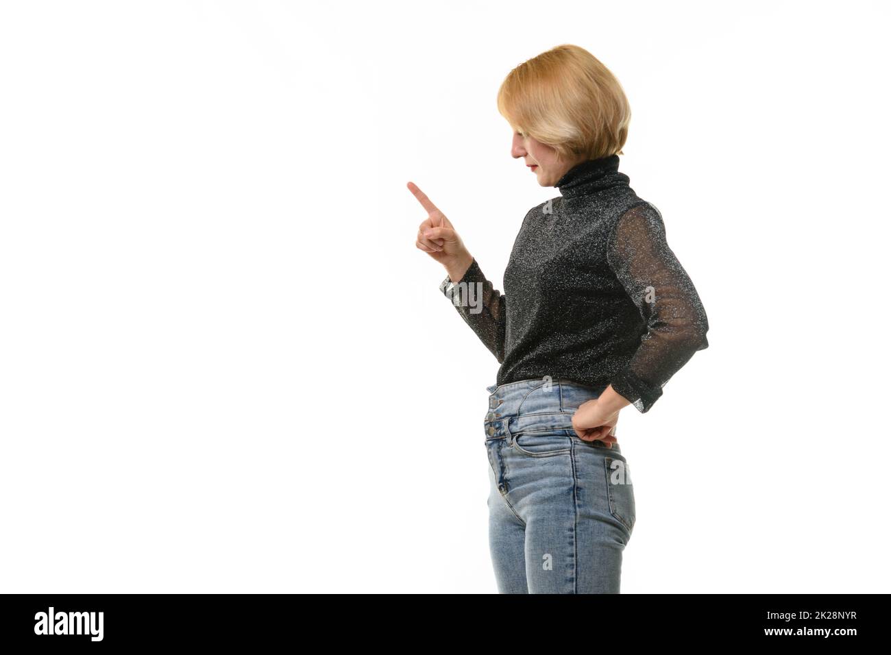 La donna guarda a sinistra e ha alzato il dito indice in modo guerrioso, isolato su sfondo bianco Foto Stock