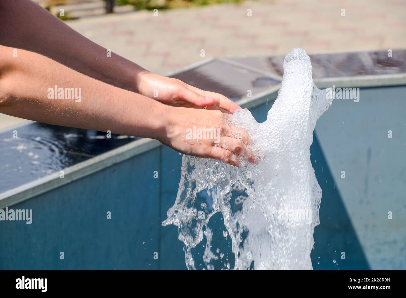 La mano toccare la fontana. Un flusso di acqua dalla fontana è toccato a mano Foto Stock