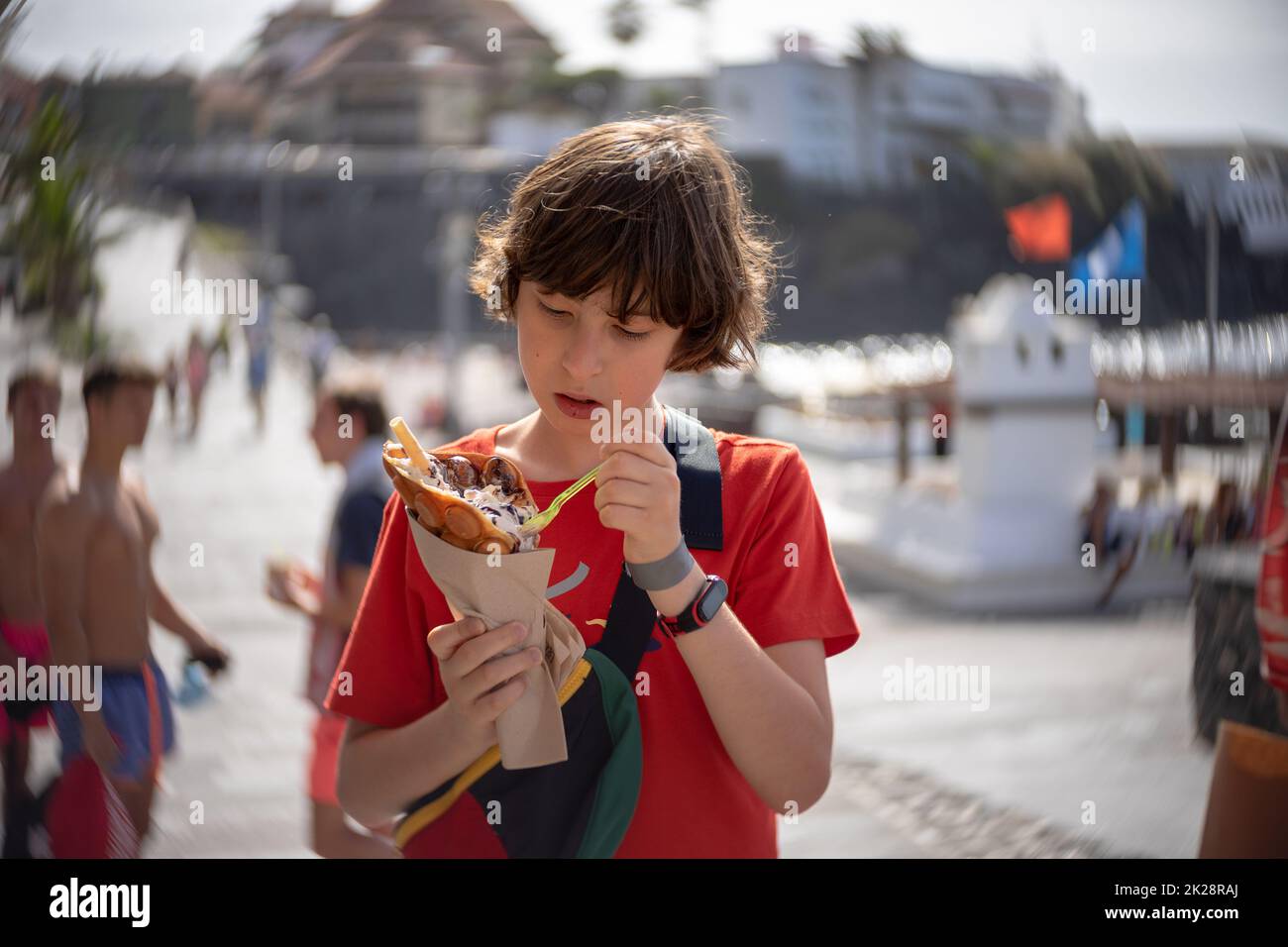 Un adolescente mangia un waffle a forma di bolla sul lungomare di Puerto de la Cruz. Tenerife. Isole Canarie. Spagna. Foto Stock