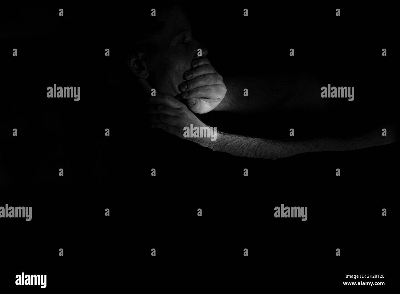 La mano di un uomo chiude la bocca e strangolare una ragazza al buio, violenza e paura, violenza contro una donna, un assassino Foto Stock