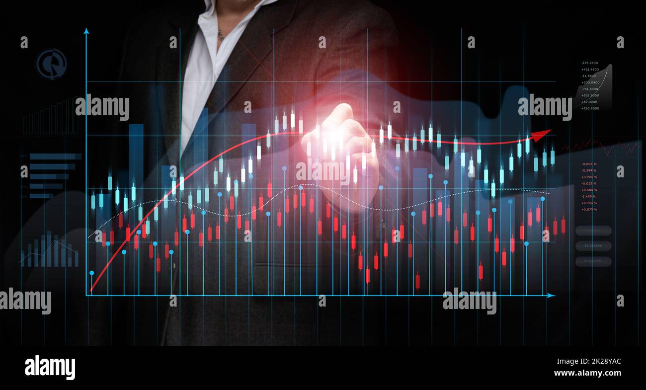 un uomo d'affari in un vestito si leva davanti ad un grafico olografico con le figure crescenti, la crescita di affari, reddito alto. Negoziazione in borsa Foto Stock